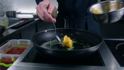 Chef cook puts ravioli in frying pan with butter and rosemary at electric stove. Cook prepares food for guests. Process of making gourmet dishes. Concept of working on restaurant kitchen. Close up. - Powered by Adobe