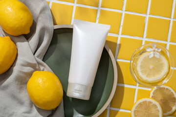 Top view of white cosmetic container and a towel placed on a dish displayed with a glass of Lemon...