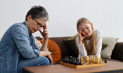An intense chess match between a woman and a child in a home interior.