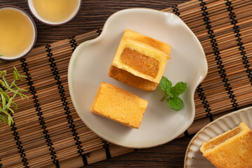 Delicious pineapple cake pastry in a plate on wooden table background with tea.