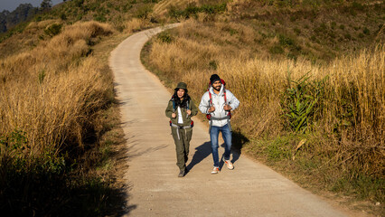 Obraz premium Happy Travelers Hiking with Backpacks on the Beautiful Rocky Trail at Warm Sunny. Hikers with backpacks walks in mountains. travel in the mountains with backpacks. Travel in the mountain with backpack
