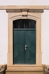 Obraz premium Green wooden door in a baroque sandstone portal with a keystone on the facade of Pfarrhaus building in Staudernheim, Germany