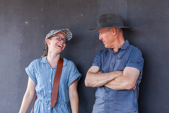 Happy young adult daughter talking with her dad standing against wall