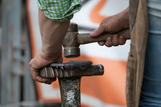 Close up of a farrier shaping a horse shoe with a hammer