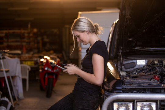 Female mechanic checking her transactions on her phone