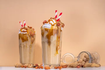 Foto op Plexiglas Peanut butter smoothie, milk shake with a lot of peanuts and caramel sauce, beige background copy space © ricka_kinamoto