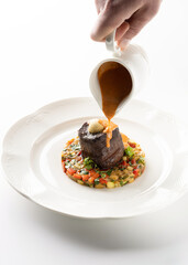 meat with vegetables with sauce in a white plate on a white background