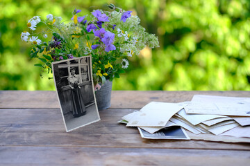 old vintage photographs, bouquet of wild flowers on table wooden table in garden, beautiful blurred...