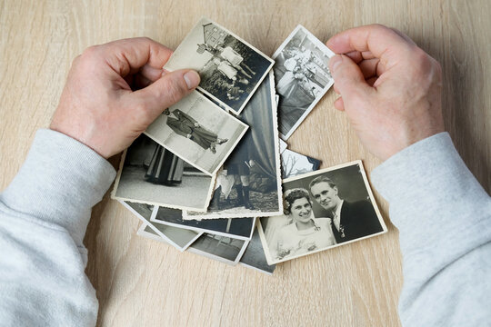 an elderly man looks through his old photographs of 1950-1955, the concept of nostalgia and memories of youth, childhood, remembering his life, relatives, family connection of generations