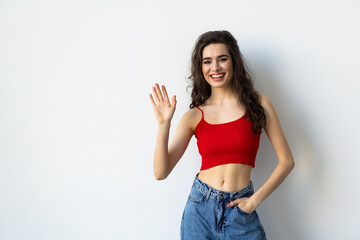 Friendly woman say hi and wave hand cheerful, smiling at camera to greet you, standing against white background