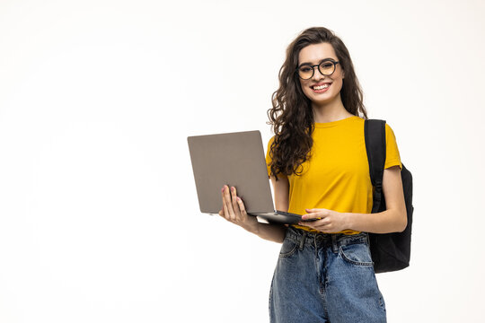 Happy student girl with backpack standing and holding laptop isolated on a white background