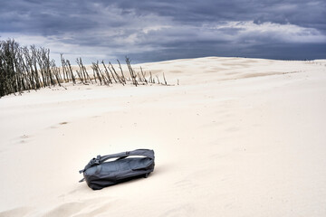 shifting sand dune of Leba, Poland, with a lost backpack in the foreground