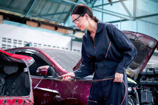 Portrait of beautiful female auto mechanic in uniform welding car body panel, auto mechanic technician woman fixing, repairing maintenance customer car automobile at garage vehicle repair service.