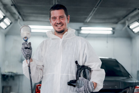 Mechanic man in white costume cloth holding chemical protective mask before working with painting tool, auto mechanic fixing repairing vehicle at garage, technician maintenance customer car automobile