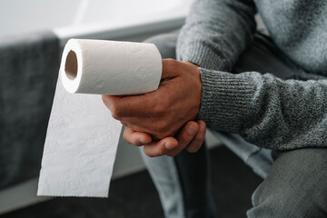 man sitting in the toilet with a paper roll in his hand