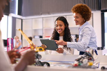 Female High School Teacher With Digital Tablet Helping Teenage Girl In STEM Technology Lesson