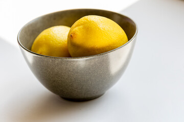 lemon in dark bowl close up on white background