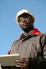 African american worker with tablet computer stands at construction site