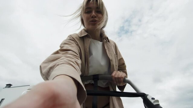 Low angle POV of happy young mother wearing casual clothes walking outdoors with baby in stroller