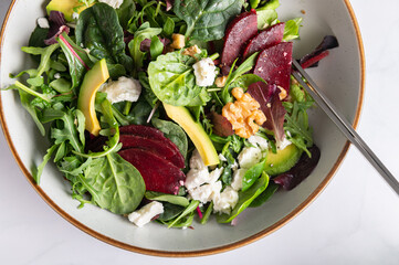 Healthy Salad made from Green Salad Leaves, Rocket Salad, Slices of Beetroot, Avocado, pieces of Feta Cheese, Walnuts and Sesame Seeds.