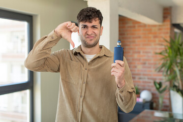 young handsome man feeling cross,showing thumbs down. vaper smoking concept