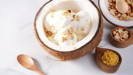 Coconut ice cream topped with roasted peanuts in a coconut shell macro shot. (spot focus)