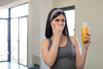 pretty young woman feeling scared, worried or angry and looking to the side. orange juice concept