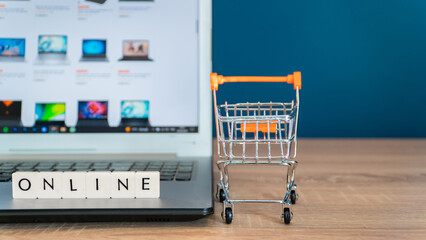 Online shopping concept. Black friday shopping online. Shopping cart or trolley and laptop on...