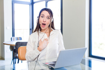 young pretty woman looking shocked and surprised with mouth wide open, pointing to self....