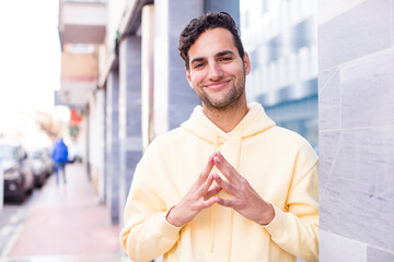 young hispanic man scheming and conspiring, thinking devious tricks and cheats