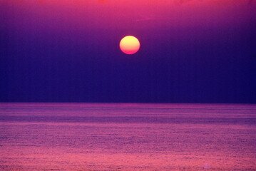 紫色に染まる夕焼けの海に沈む夕日