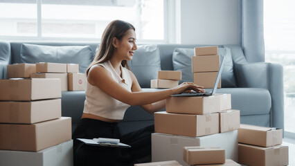 Using laptop, Portrait of pretty asian sme freelancer woman checking customer paid order on sofa after packing into cardboard box, online home small business, online influencer asia people.