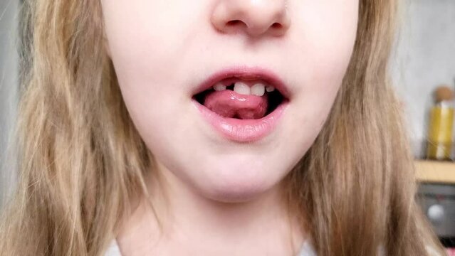 portrait of a little child girl moving her milk front tooth with her tongue in open mouth.
