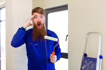 red hair man looking happy, astonished and surprised repairing home. handyman concept