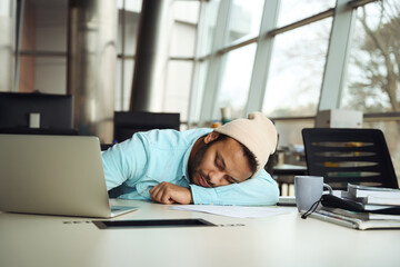 Man in hat relaxing on desk in the office