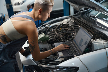 Craftswoman with a short haircut conducts computer diagnostics of car