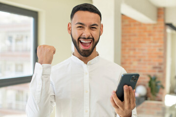 young  adult man feeling shocked,laughing and celebrating success. smartphone concept