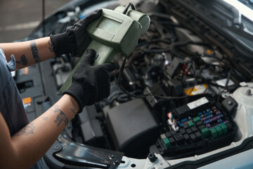 Car mechanic with a tattoo works under the hood