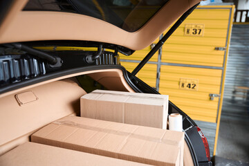 Cardboard boxes lying in the automobile trunk in the warehouse