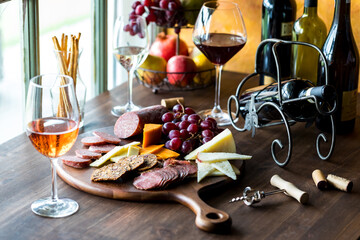 A charcuterie board of gourmet meats and cheese with red, white and rose wine.