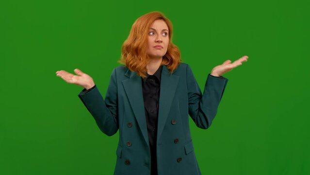 Female red haired doubting and shrugging shoulders as indecision and insecurity over green screen background. Woman making unimportant and doubts gesture lifting the shoulders and palms of the hands.