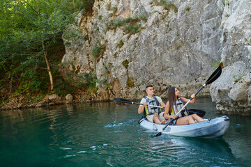 A young couple enjoying an idyllic kayak ride in the middle of a beautiful river surrounded by forest greenery