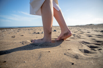 Close-up of a girl's feet at the beach, woman walking barefoot on the sand.