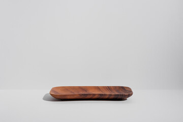Empty wooden plate on light grey background. Wooden podium for food or cosmetic product mockup. Showcase for product presentation. Front view, copy space for text. Minimal composition.