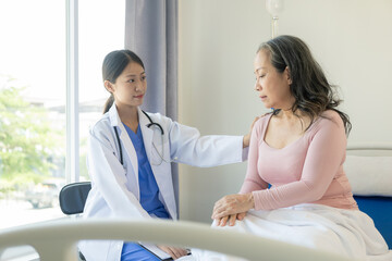 Obraz premium Asian elderly woman smiling happily talking and being comforted by a female doctor who speaks to an elderly woman at a desk explaining the results of the examination, examination, treatment
