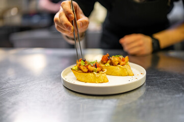 chef hand cooking Prawns, shrimp seafood bruschetta with creamy cheese on restaurant kitchen