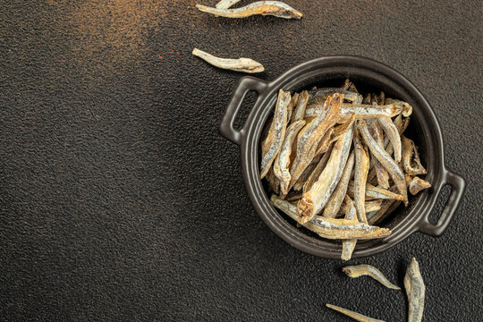 Fresh dried anchovies on dark background. Raw dry salted sea fish on a dark background. place for text, top view