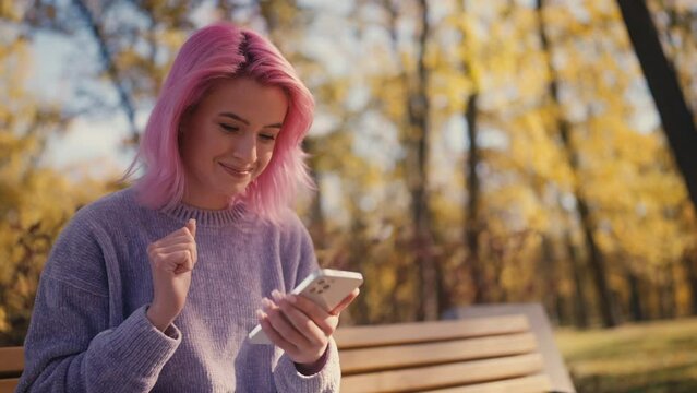 Young pink-haired woman wearing braces using her smartphone, social media user