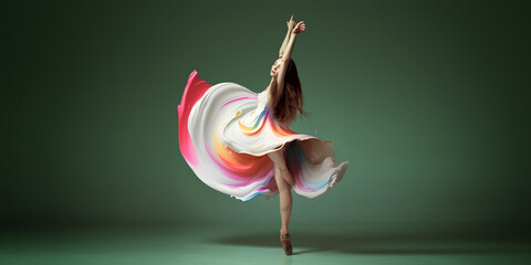 Portrait with one young woman, classic dancer dancing in colorful painted dress over dark green background. Contemporary dance style, ballet - obrazy, fototapety, plakaty