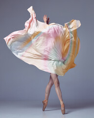 Young woman, ballerina dancing with elegance movements and fabric cover the face over grey studio background. Ballet with silk © Lustre Art Group 